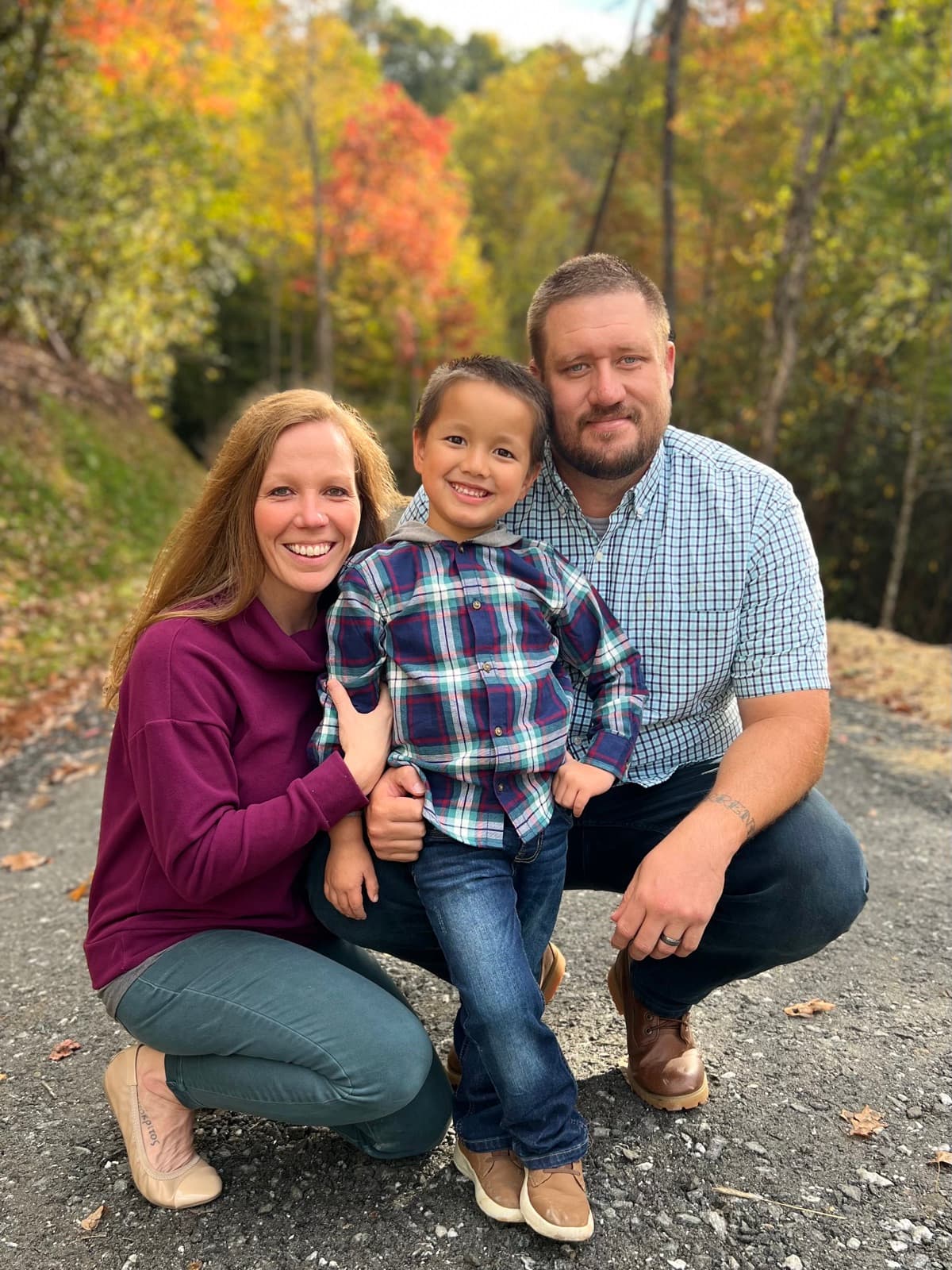 Donovan, Elizabeth, and Brooks Turnmire outdoors with fall foliage behind them